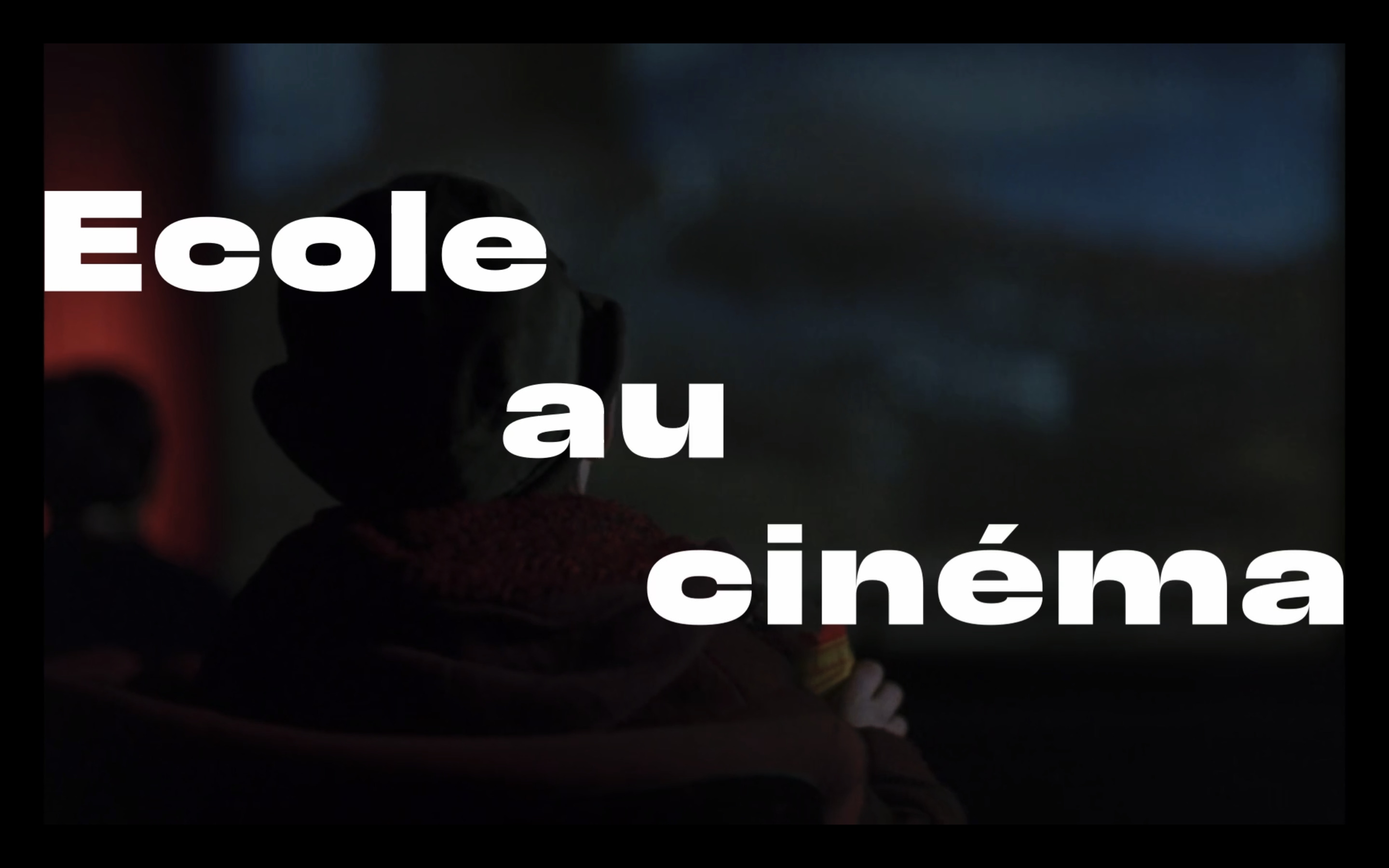 L'intertitre d'École au Cinéma tiré du film 'Le Cheval venu de la mer' où un petit garçon de dos regarde un film au cinéma. Sur l'image se trouvent les mots 'Ecole au cinéma'.
